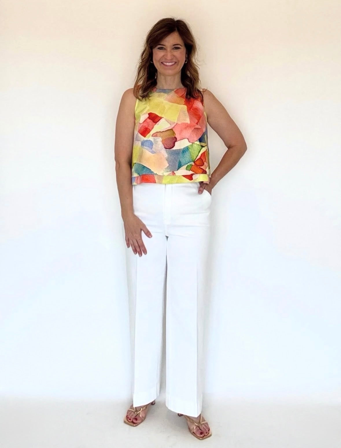 A woman wearing a round neck, sleeveless blouse in a yellow watercolor print.