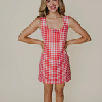 Woman wearing a red and white checkered dress against a beige background
