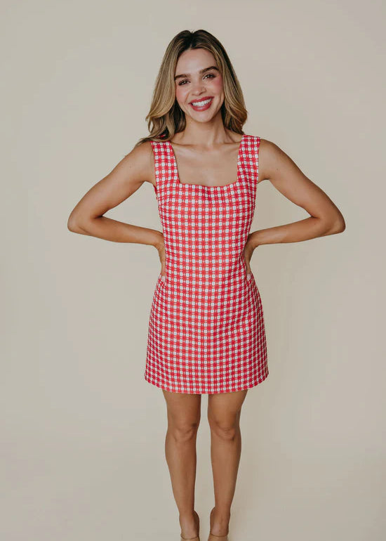 Woman wearing a red and white checkered dress against a beige background