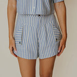 Person wearing a blue and white striped outfit with a plain background