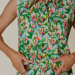 Person wearing a sleeveless dress with a floral pattern on a plain background