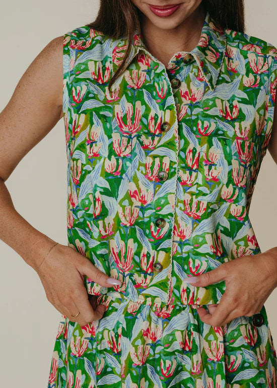 Person wearing a sleeveless dress with a floral pattern on a plain background
