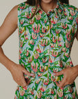 Person wearing a sleeveless dress with a floral pattern on a plain background