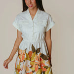Woman wearing a white dress with floral pattern on a beige background