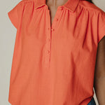 Orange blouse worn by a person with a neutral background