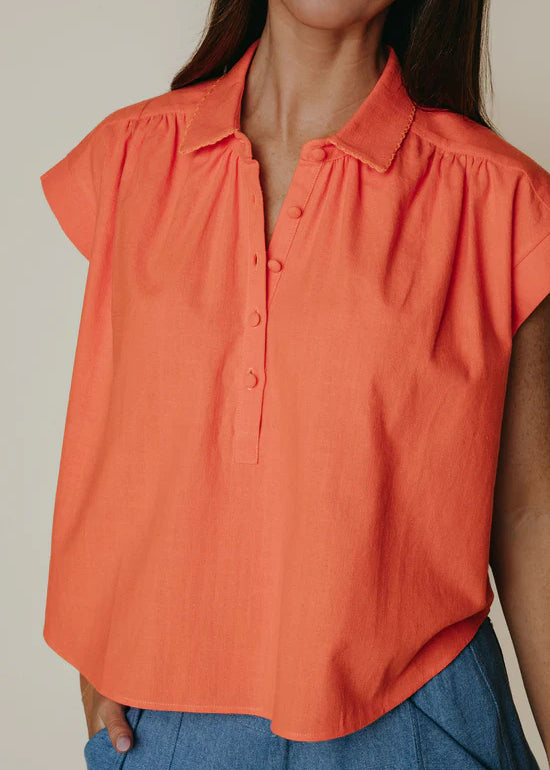 Orange blouse worn by a person with a neutral background