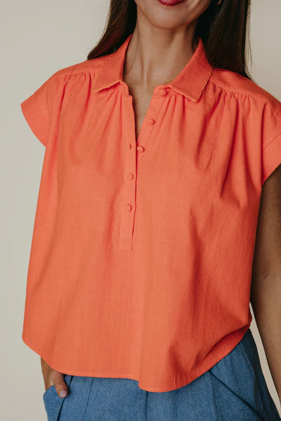 Orange blouse worn by a person with a neutral background