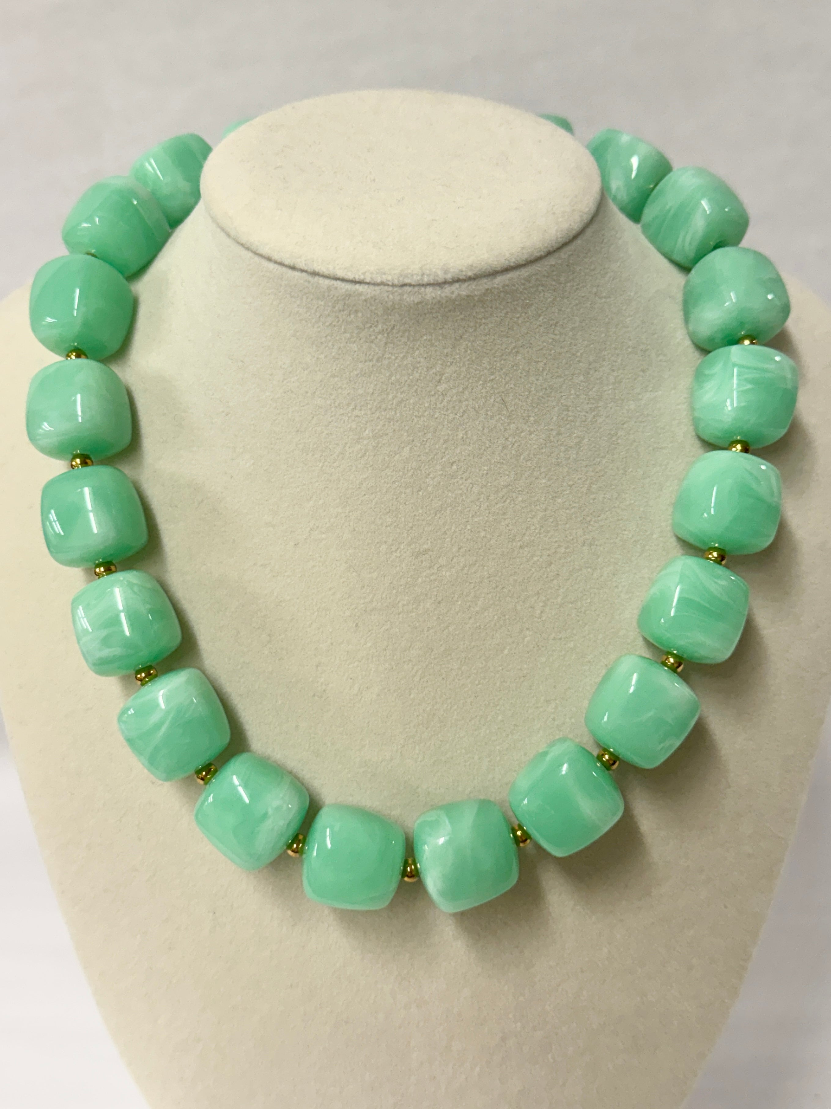 Green beaded necklace on a white mannequin bust