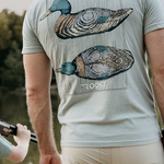 Man wearing a t-shirt with a mallard duck design and 'ROOST' branding outdoors.