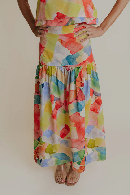 A woman wearing a yellow multicolor skirt that looks watercolors.