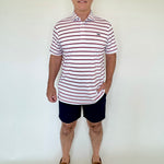 Man wearing a striped polo shirt and shorts against a white background