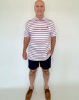 Man wearing a striped polo shirt and shorts against a white background