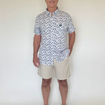 Man wearing a patterned shirt and beige shorts against a white background