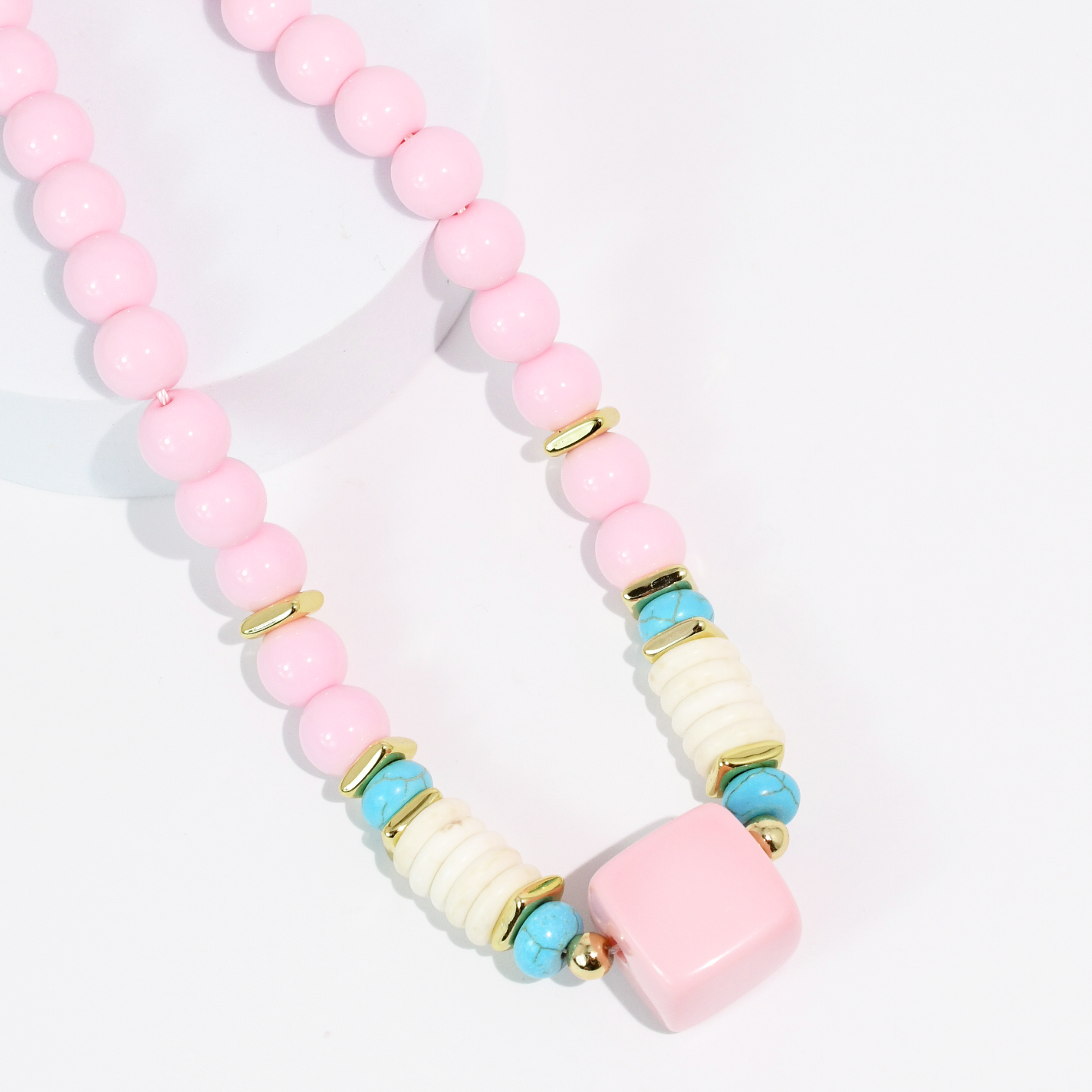 Necklace with pink, blue, and gold beads on a white background