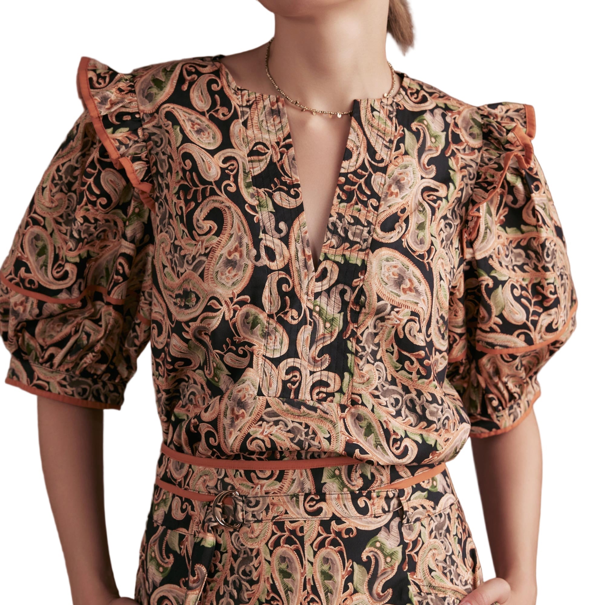 Person wearing a paisley patterned blouse with puff sleeves on a white background