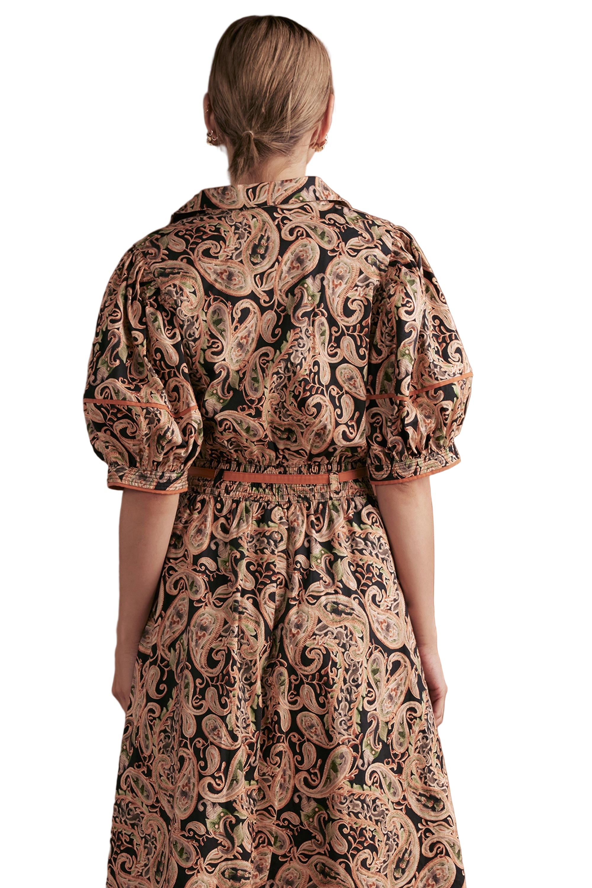 Woman wearing a paisley patterned blouse against a white background