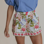 a woman wearing white dressy shorts with blue and pink florals.