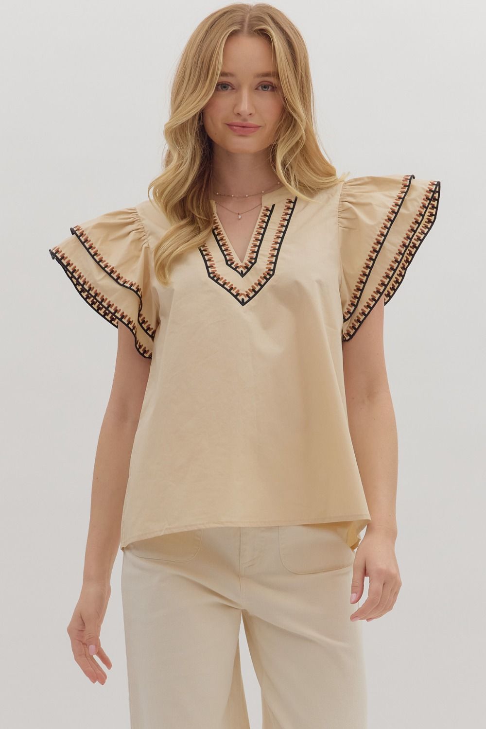 Woman wearing a beige blouse with decorative sleeves on a white background