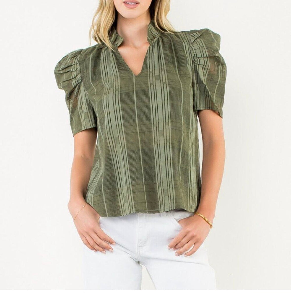 A mesh check print olive green blouse that is v-neck and has puff sleeves.