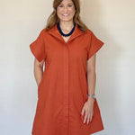 Woman wearing a rust-colored dress against a plain background