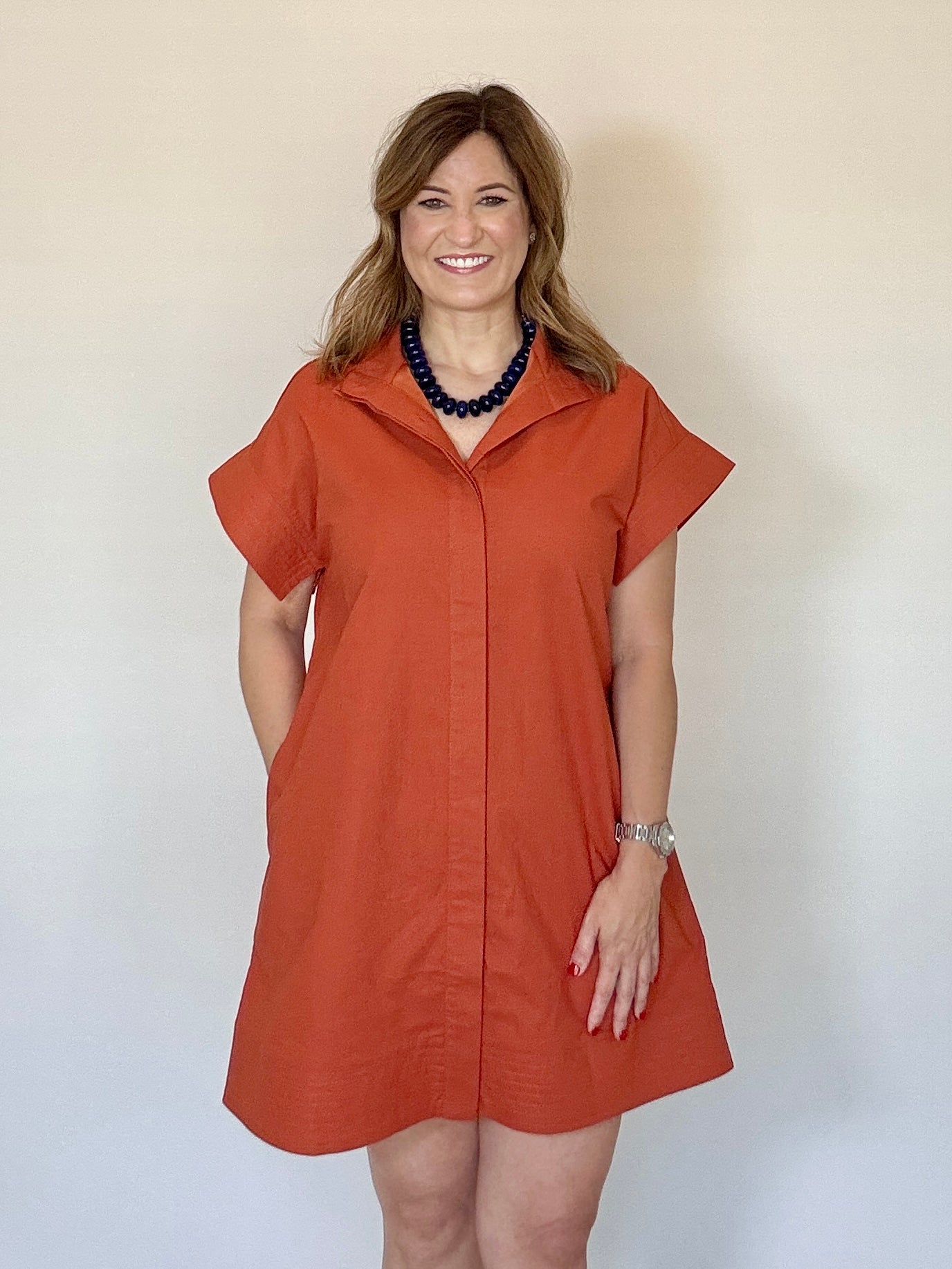 Woman wearing a rust-colored dress against a plain background