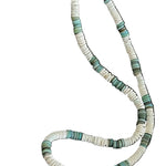 Necklace with green and white beads on a dark surface