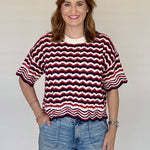 Woman wearing a red, white, and blue striped shirt with denim shorts on a plain background