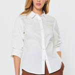 A woman wearing a white collared button down blouse with 3/4 sleeves.