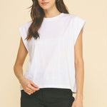 Woman wearing a white sleeveless top and black shorts on a beige background
