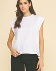 Woman wearing a white sleeveless top and black shorts on a beige background