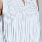 White pleated sleeveless top worn by a person on a light gray background