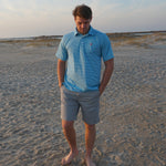 A man modeling the Albatross Performance Golf Polo in Aruba/Regatta Stripe by Bald Head Blues, styled with casual pants, from Chatsworth Boutique.