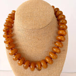 Brown beaded necklace on a beige mannequin head against a white background