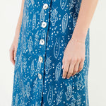 A model posing in the Button Detail Fish Skirt by THML, a cotton midi skirt with a playful fish print, from Chatsworth Boutique in Fairhope, Alabama.