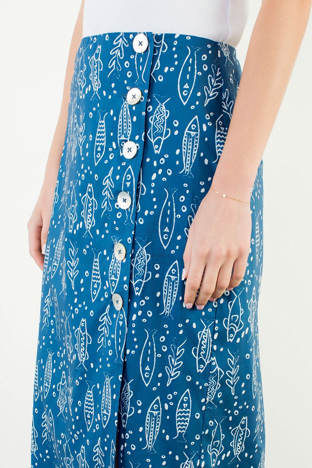 A model posing in the Button Detail Fish Skirt by THML, a cotton midi skirt with a playful fish print, from Chatsworth Boutique in Fairhope, Alabama.