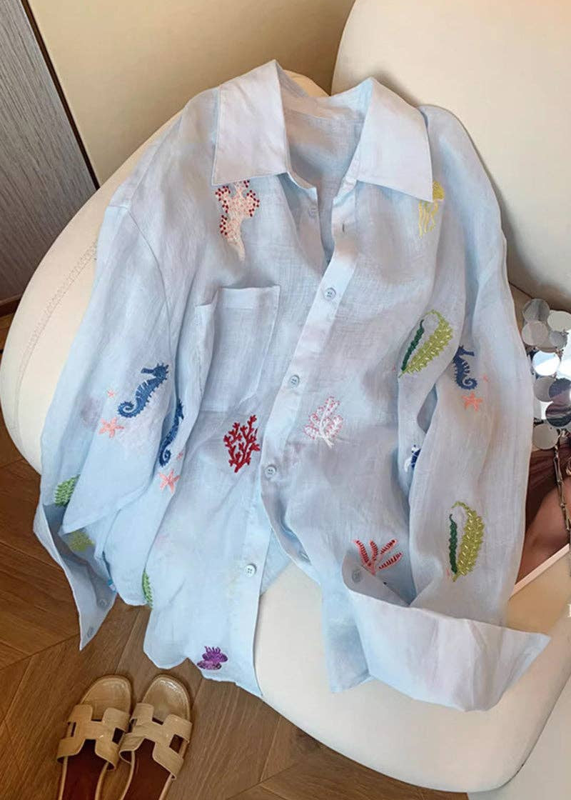Light blue shirt with colorful embroidery on a white chair.