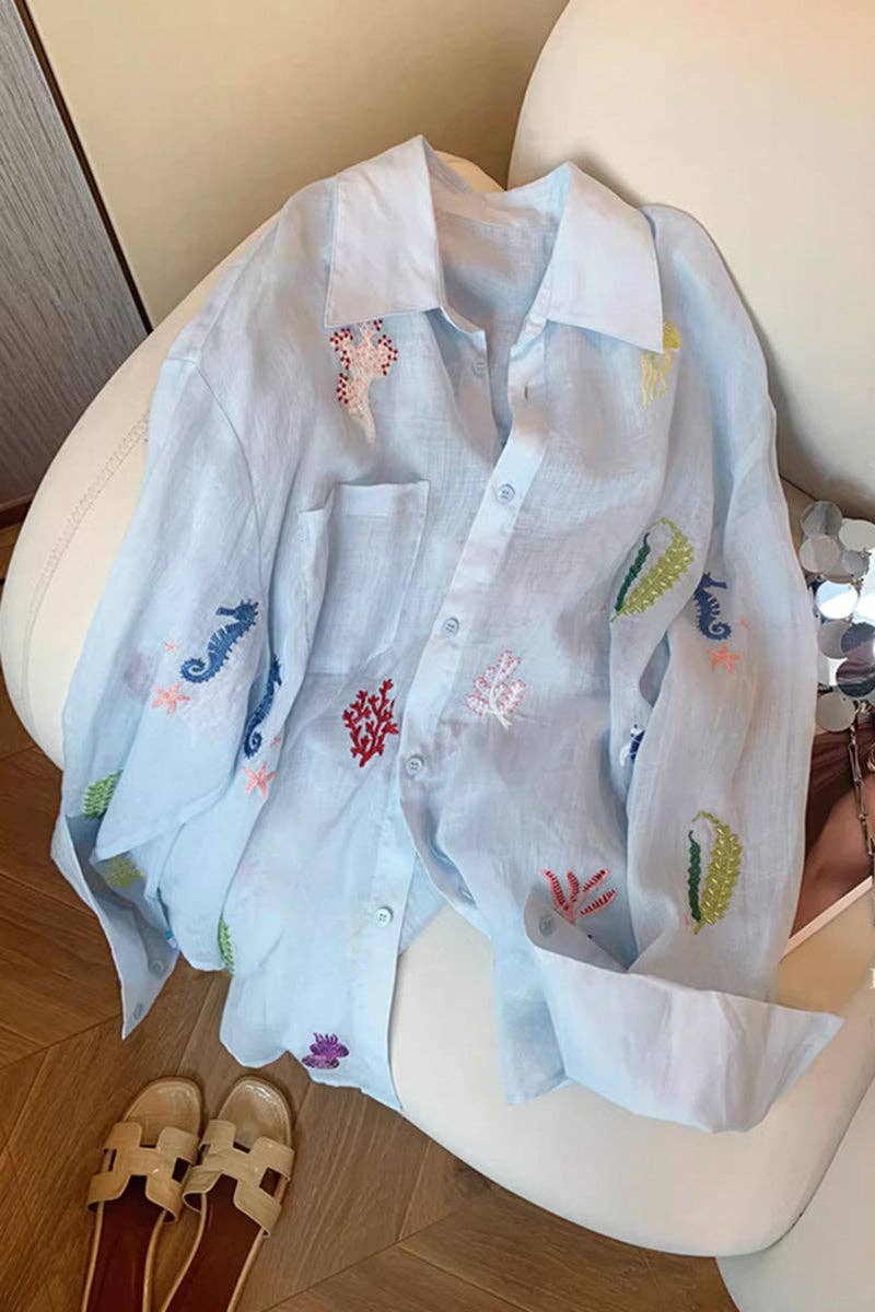 Light blue shirt with colorful embroidery on a white chair.