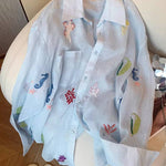 Light blue shirt with colorful embroidery on a white chair.