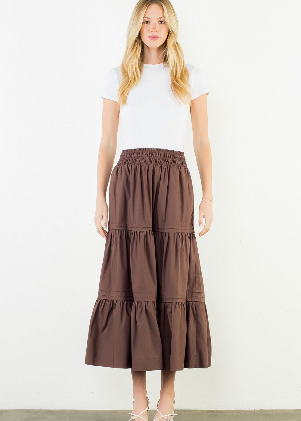 A model wearing the Chocolate Tiered Midi Skirt by THML, a cotton tiered midi skirt in chocolate, from Chatsworth Boutique in Fairhope, Alabama.