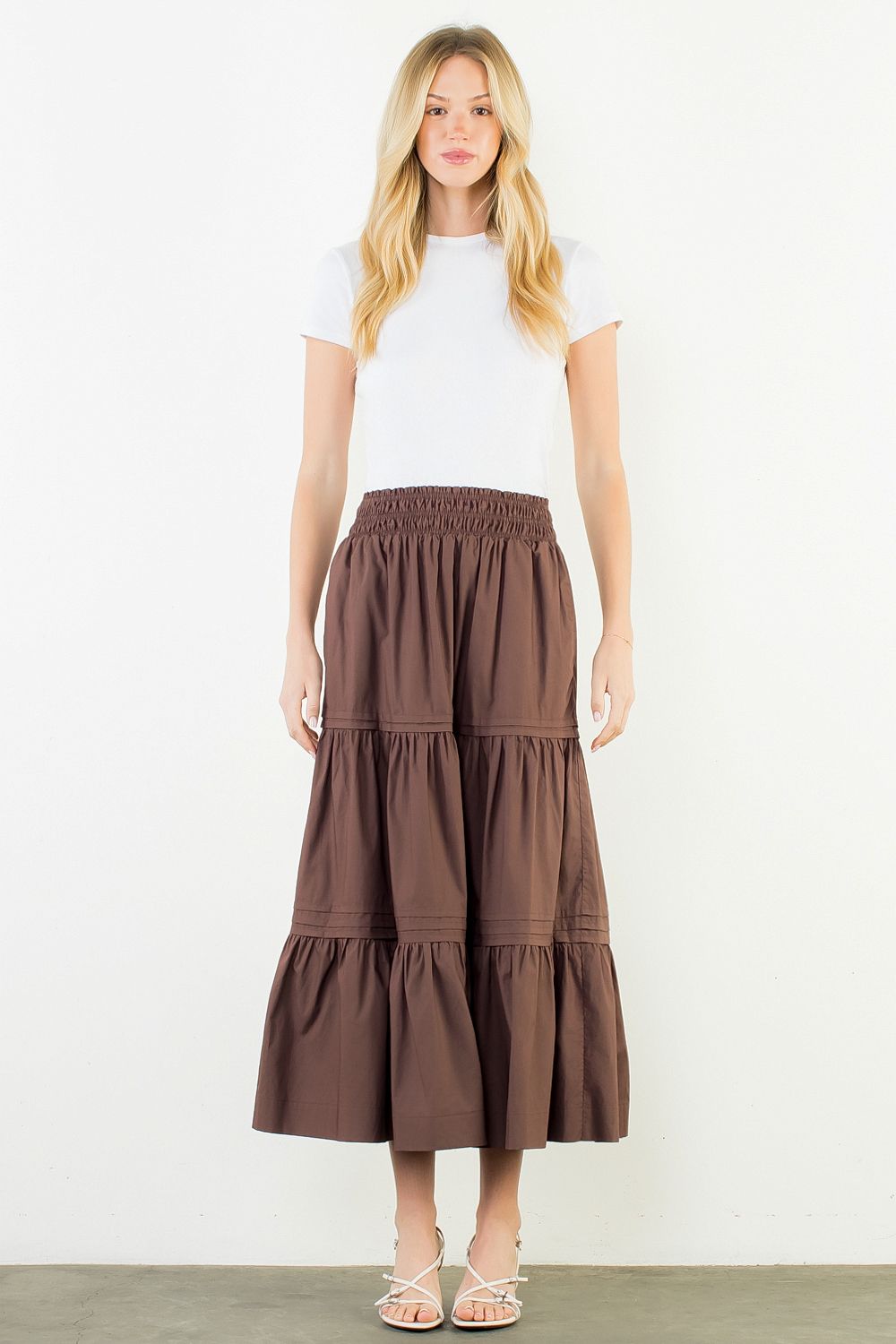 A model wearing the Chocolate Tiered Midi Skirt by THML, a cotton tiered midi skirt in chocolate, from Chatsworth Boutique in Fairhope, Alabama.