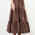 A model posing in the Chocolate Tiered Midi Skirt by THML, a 100% cotton midi skirt, from Chatsworth Boutique in Fairhope, Alabama.