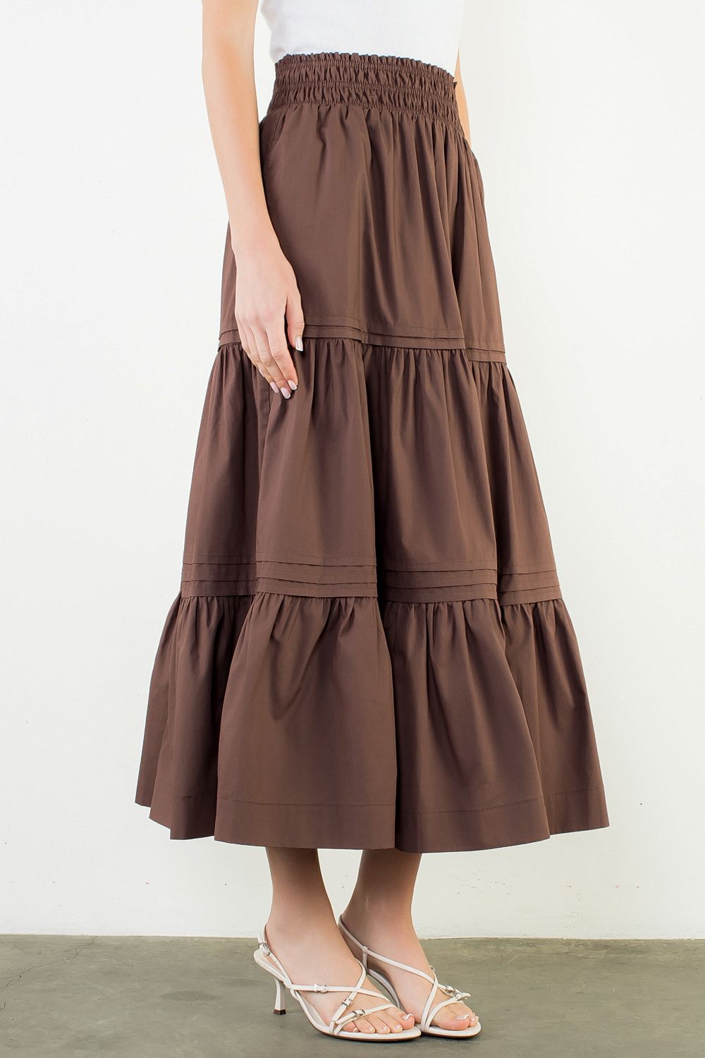 A model posing in the Chocolate Tiered Midi Skirt by THML, a 100% cotton midi skirt, from Chatsworth Boutique in Fairhope, Alabama.