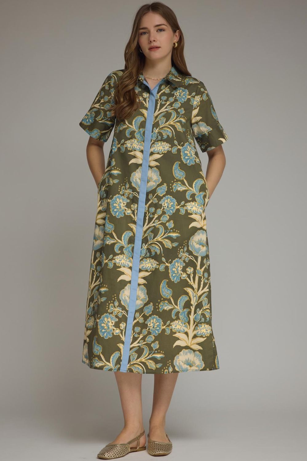 A model wearing the Contrast Trim Shirtdress Midi by Entro, an olive floral print midi dress with contrast blue trim on the button placket, from Chatsworth Boutique in Fairhope, Alabama.