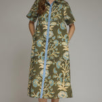 A model wearing the Contrast Trim Shirtdress Midi by Entro, an olive floral print midi dress with contrast blue trim on the button placket, from Chatsworth Boutique in Fairhope, Alabama.