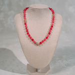 Necklace with red beads on a beige mannequin bust against a gray background
