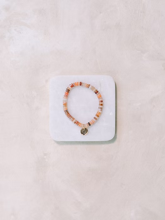 Beaded bracelet on a white stone display block against a light  background