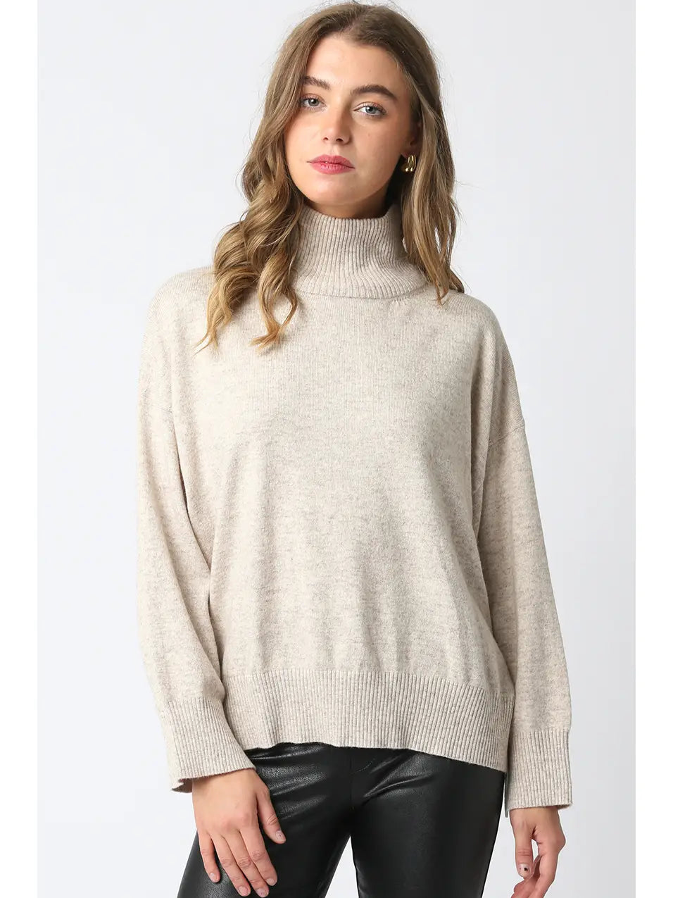 Woman wearing a beige turtleneck sweater against a white background