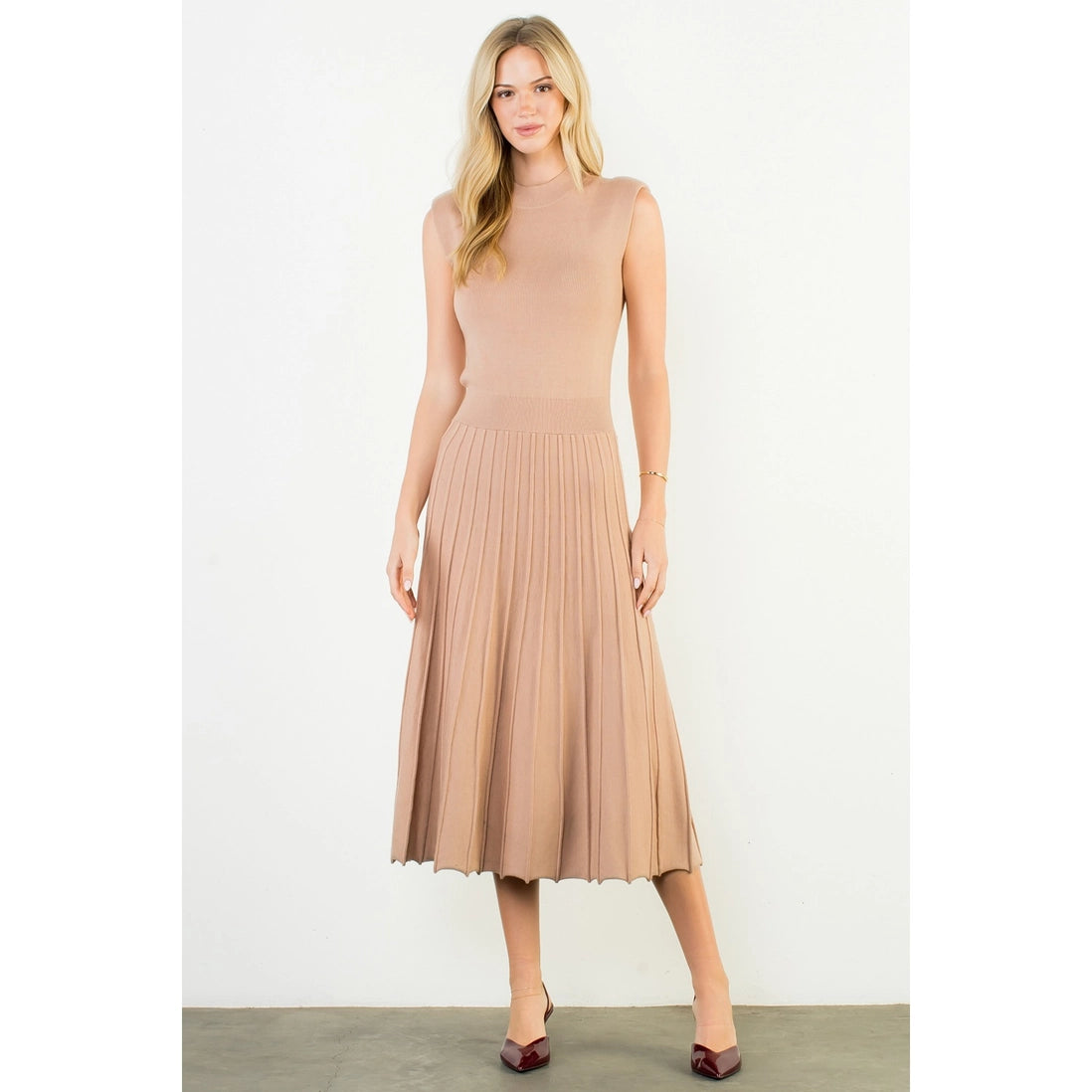 Woman wearing a beige pleated dress on a white background