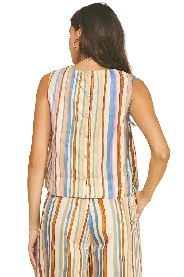 Woman wearing a colorful striped sleeveless top and pants on a beige background