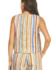 Woman wearing a colorful striped sleeveless top and pants on a beige background